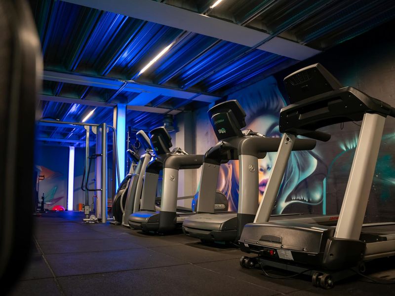 Atmospheric low light gym with neon accents and cardio equipment